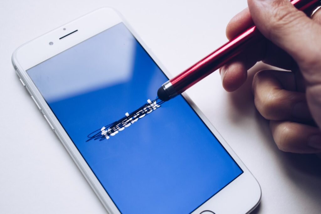 pencil erasing lines on an iPhone screen showing the Facebook logo