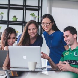 four people watching a viral video on a macbook